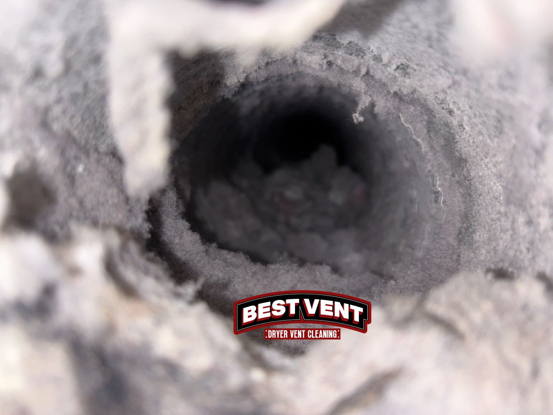 Thick layers of grey lint and debris clogging the inside of a circular dryer vent.