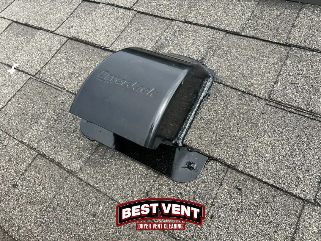 Black DryerJack roof vent installed on a grey shingled roof for efficient dryer exhaust.