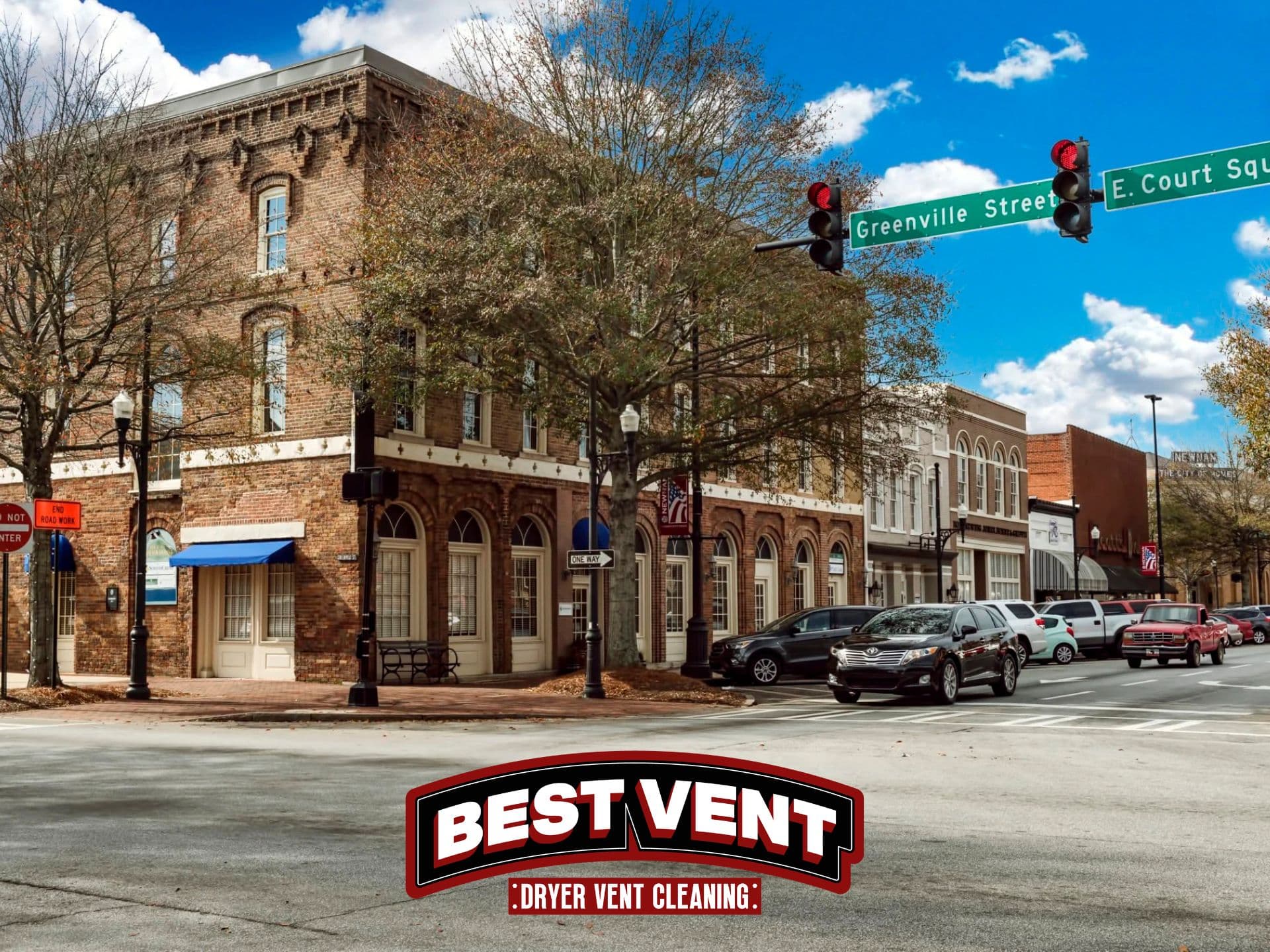 Sunny street corner featuring brick buildings and a Best Vent Dryer Vent Cleaning logo.