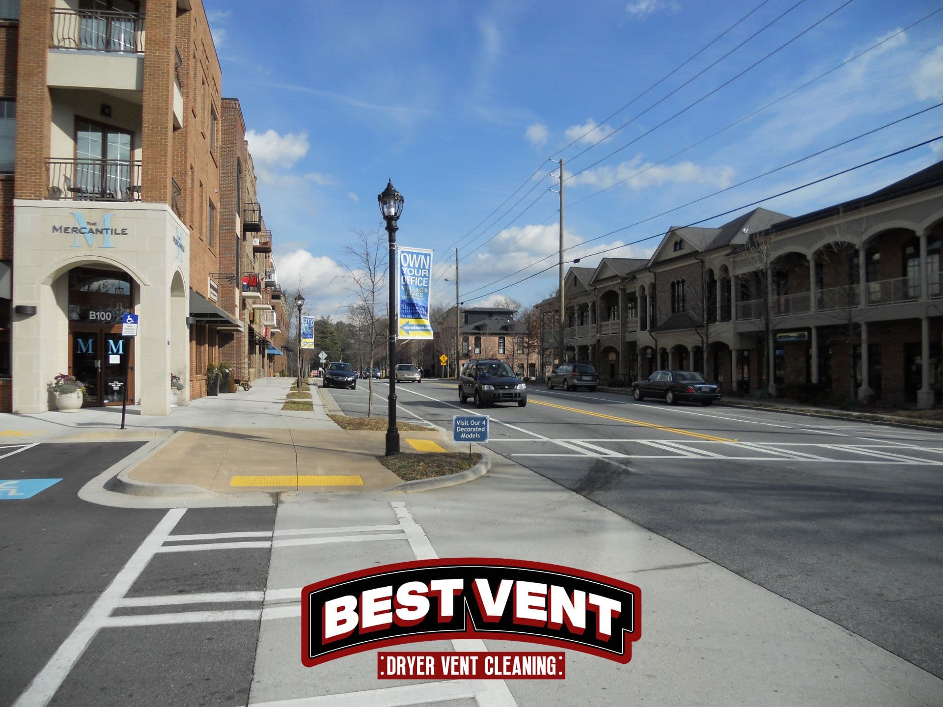 Sunny street with brick buildings and cars, featuring a Best Vent Dryer Vent Cleaning logo.
