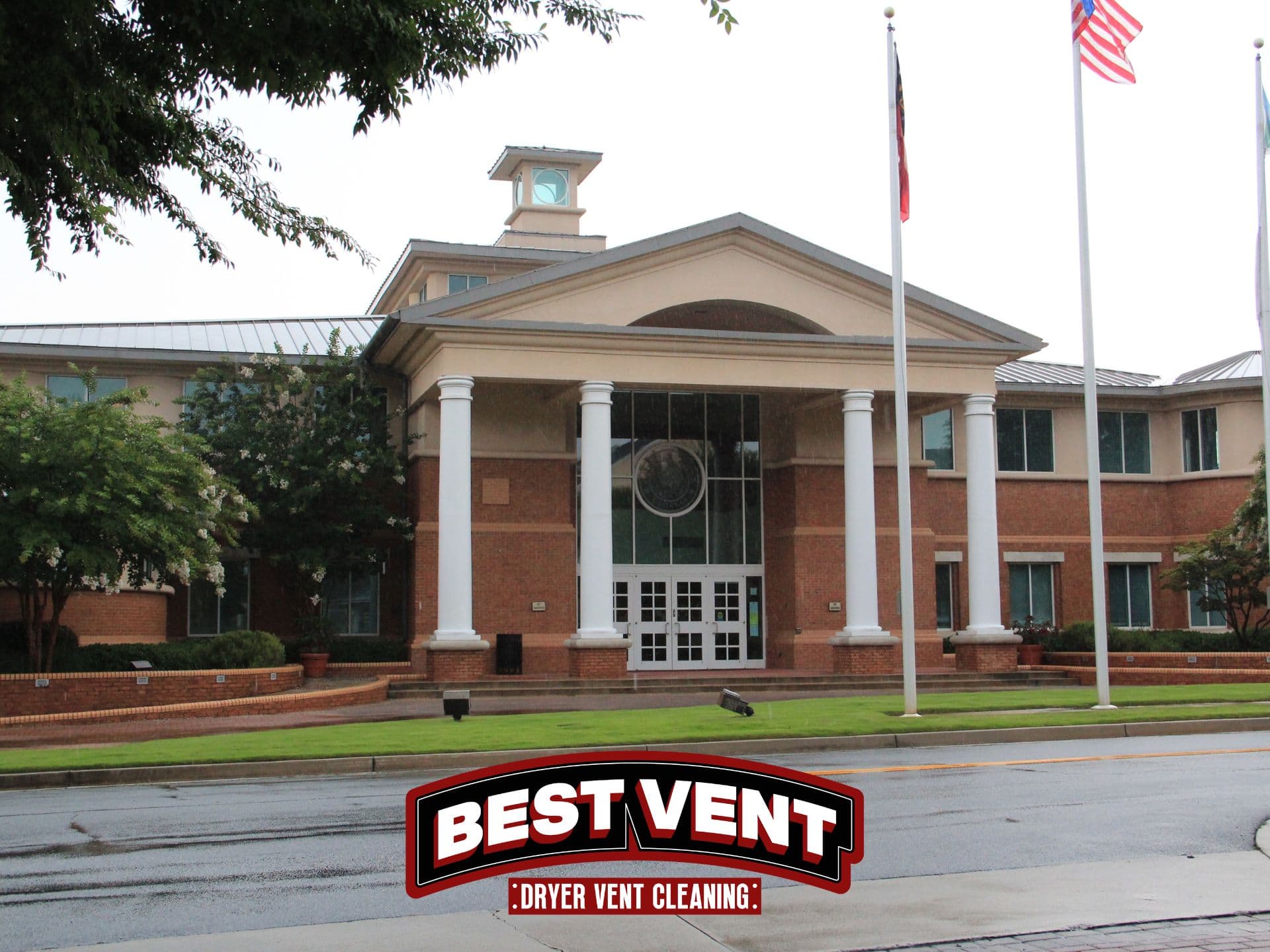 Large brick building with white columns and flags, featuring Best Vent Dryer Vent Cleaning logo.