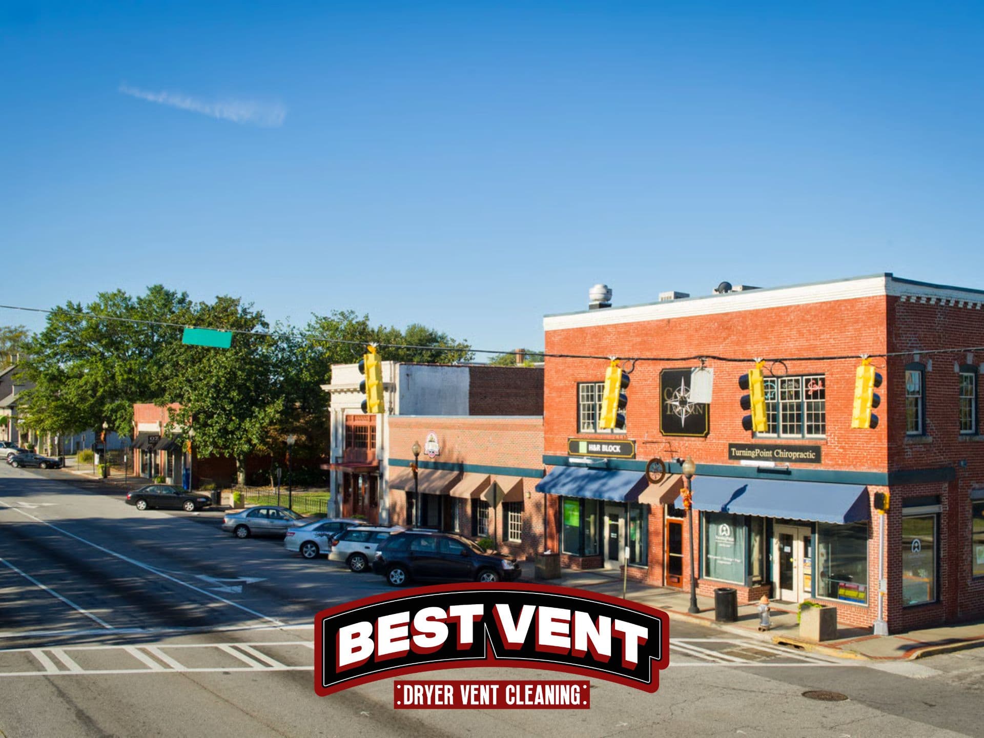 Sunny small town street corner with brick buildings and Best Vent Dryer Vent Cleaning logo.