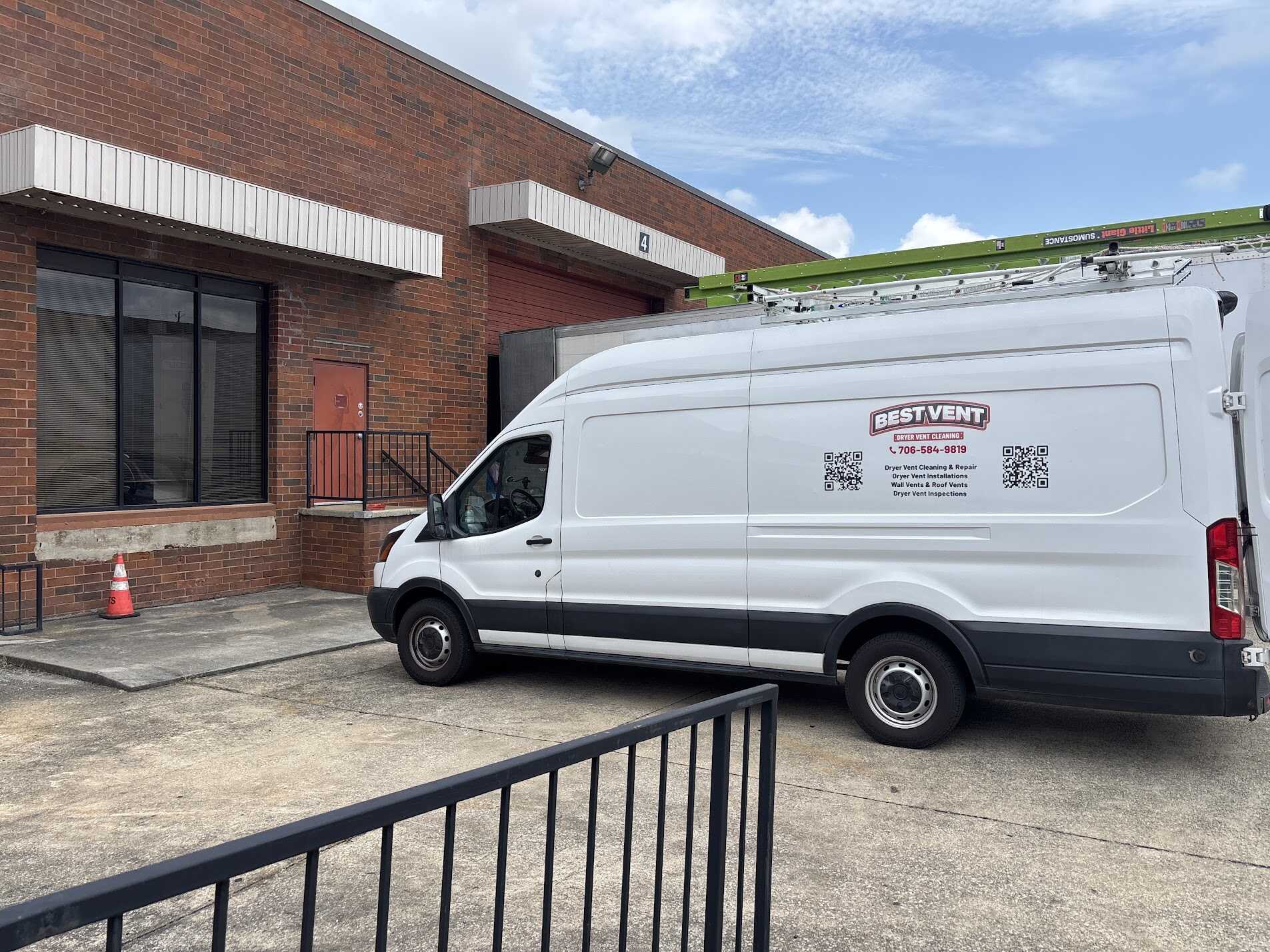 White Best Vent service van with a ladder parked outside a red brick commercial building.